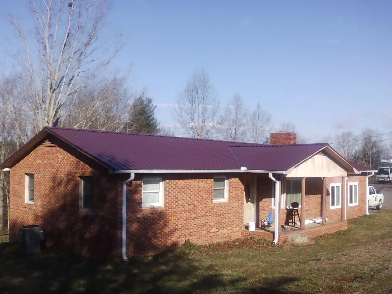 Burgundy metal roof on a brick ranch home with a new addition in Spencer